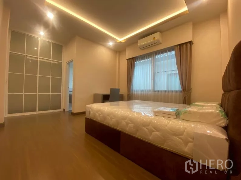 独立式住宅 出租在Prawet, Bangkok - 卧室配嵌入式衣柜、书桌与木地板。