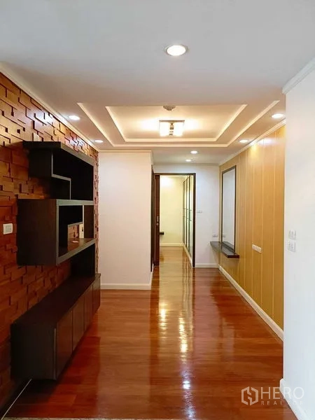 公寓 出租在Watthana, Bangkok - 走廊与起居区，吊顶筒灯，木质特色墙与搁架，亮面木地板。