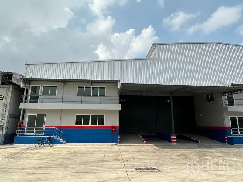 货栈 出租在Samut Prakan - 仓库外观，带两层办公区、带顶装卸坡道和宽阔车道的现代厂房