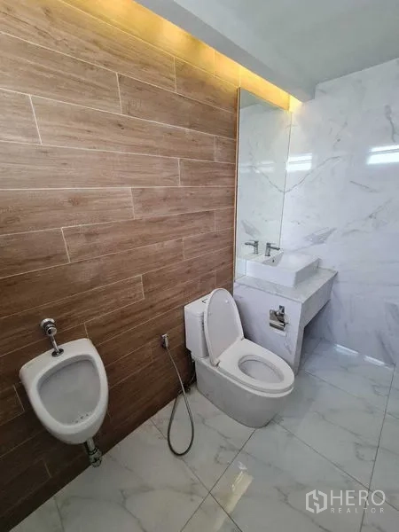 Office Space for rent - Modern restroom featuring marble-look tiles, wood accent wall, toilet, urinal and vanity.