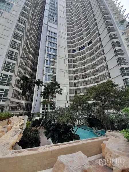 公寓 出租或出售在Pathum Wan, Bangkok - 现代高层公寓外立面弧形设计，配有棕榈与泳池花园。
