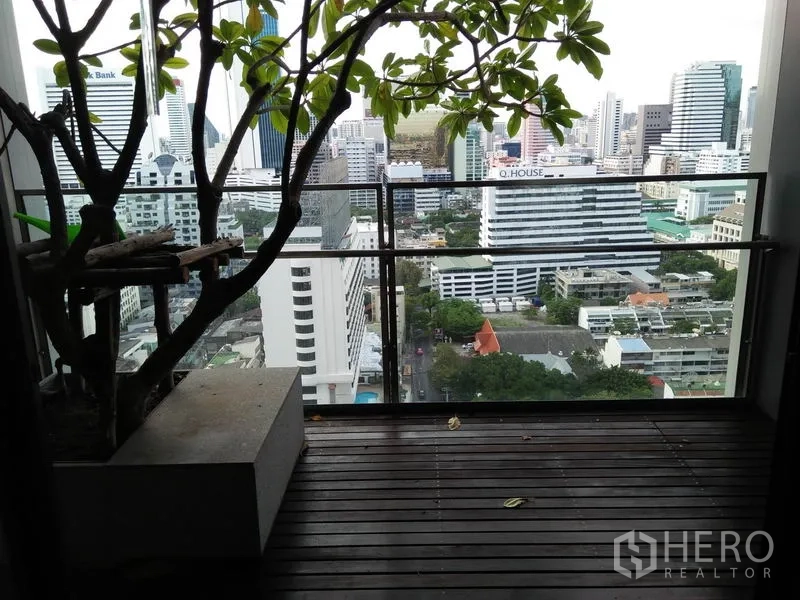公寓 出租在Sathon, Bangkok - 私人阳台木地台与玻璃栏杆，俯瞰隆比尼附近的曼谷天际线。