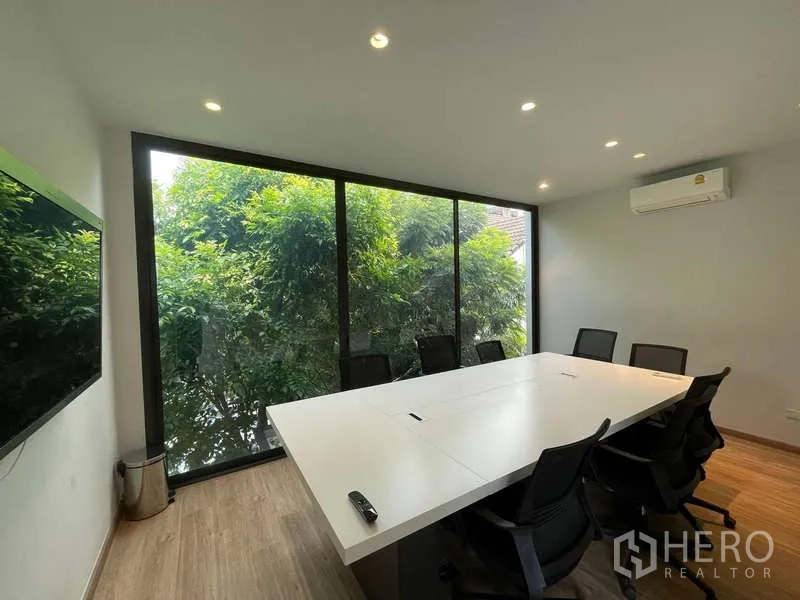 Home Office for rent in Don Mueang, Bangkok - Glass-walled meeting room with conference table, office chairs and leafy views outside.