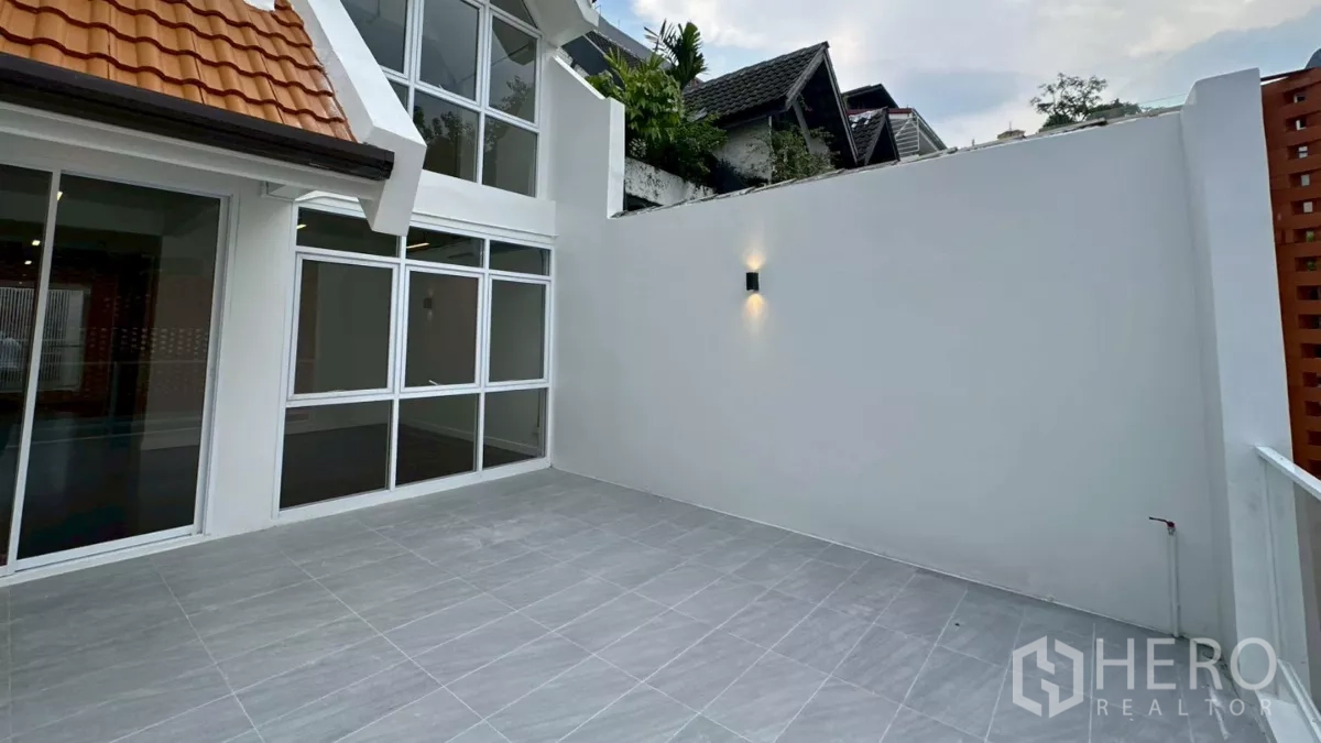 Home Office for rent in Watthana, Bangkok - Spacious tiled front terrace with high privacy walls and floor-to-ceiling windows.