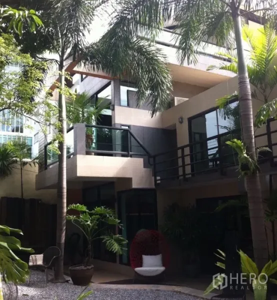 Detached House for rent in Wang Thonglang, Bangkok - Contemporary house exterior with balconies, large windows and a palm-lined courtyard.