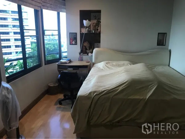 Condominium for rent or sale in Watthana, Bangkok - Bedroom with large windows, a work desk, wood floors, and a king-size bed.