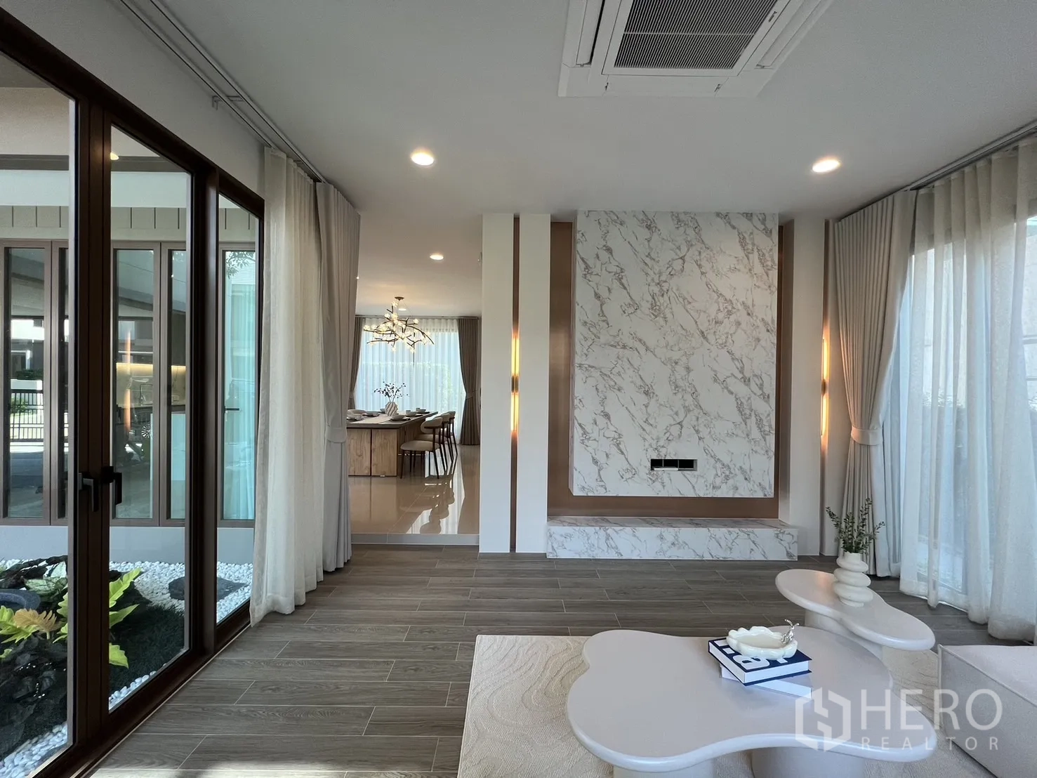 独立式住宅 出租或出售在Bang Kapi, Bangkok - 客厅通过推拉玻璃门通向庭院，可望餐厅区域。