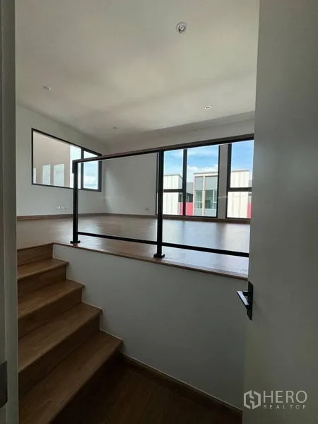 Townhouse for rent - Split-level room with wood steps, glass railing and wide windows.