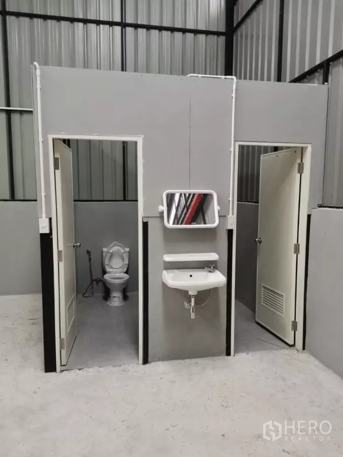 Warehouse for rent in Wang Thonglang, Bangkok - Warehouse restroom block featuring two toilet cubicles and a wall‑mounted sink.