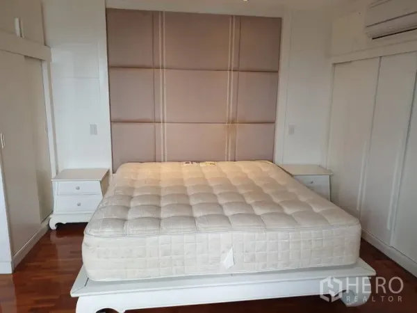 Condominium for rent in Khlong Toei, Bangkok - Master bedroom with padded headboard, king-size bed, built-in wardrobes and hardwood floors.