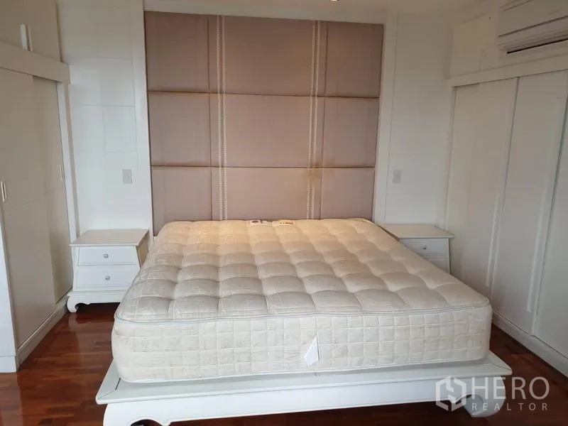 Condominium for rent in Khlong Toei, Bangkok - Master bedroom with padded headboard, king-size bed, built-in wardrobes and hardwood floors.