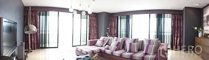 Condominium for rent in Yan Nawa, Bangkok - Spacious living room with a striped sectional sofa, floor‑to‑ceiling windows and balcony access.