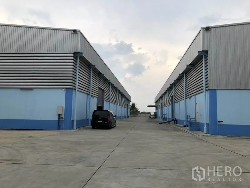 货栈 出租在Samut Prakan - 成排仓库与宽阔混凝土场地，卡车出入与停车便捷。