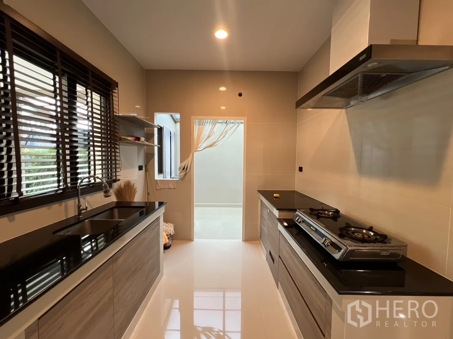 Detached House for rent or sale in Bang Kapi, Bangkok - Closed Thai kitchen with black countertops, sink and window blinds