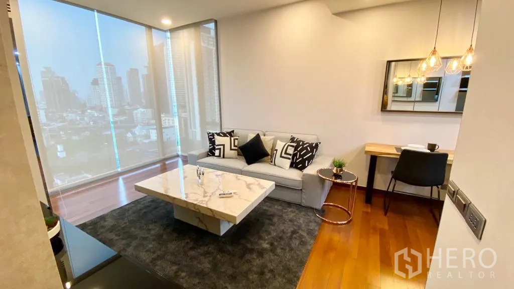 Condominium for sale in Khlong Toei, Bangkok - Cozy living room with sofa, city‑view windows and a compact dining or work desk.