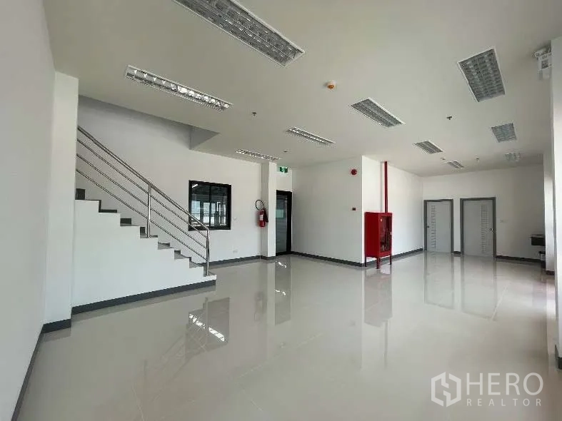 Factory for rent in Bang Sao Thong, Samut Prakan - Ground-floor office area with staircase, fire hose cabinet, and multiple doors.