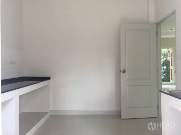 Detached House for sale in Saphan Sung, Bangkok - Minimalist white kitchen with black stone countertops and open shelves.
