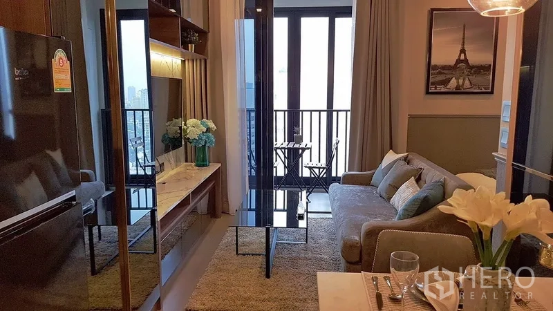 Condominium for rent in Watthana, Bangkok - Living room with TV console, glass coffee table and a balcony with city-view seating.