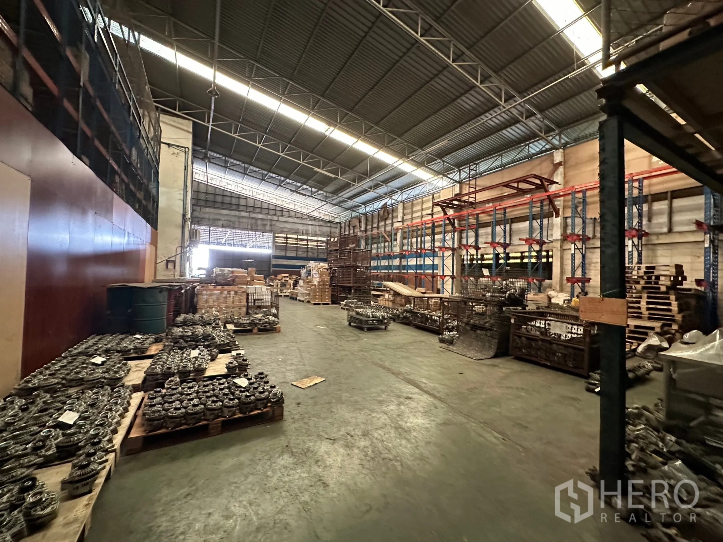 工厂 出租在Lam Luk Ka, Pathum Thani - 开放式仓储区，金属货架与托盘物料排列整齐。
