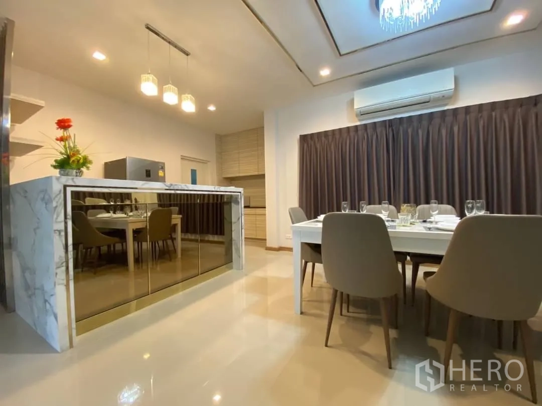 Detached House for rent or sale in Prawet, Bangkok - Dining room beside a marble island counter with full-length blackout curtains.