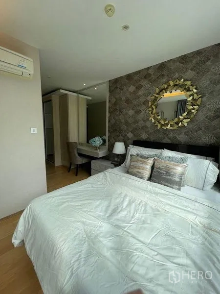 Condominium for rent in Watthana, Bangkok - Primary bedroom with feature wall, queen bed, bedside table, and dressing area with wardrobe.