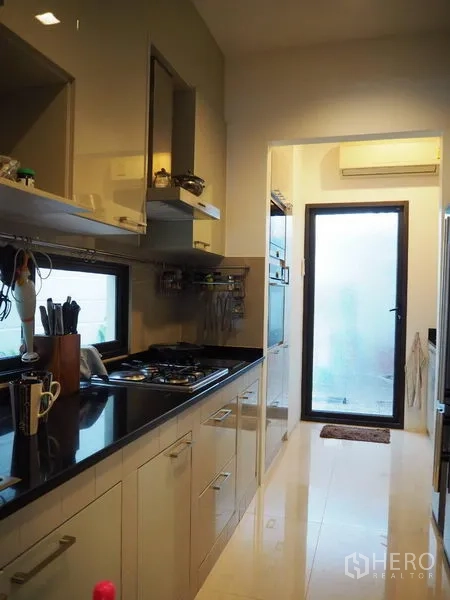 Townhouse for rent or sale in Chatuchak, Bangkok - Galley kitchen with stone countertops, gas hob, built‑ins and rear door.