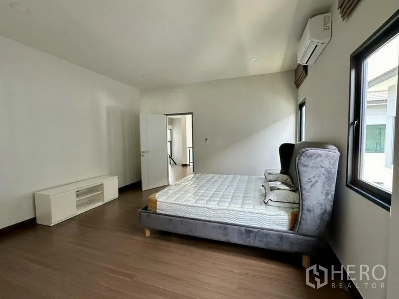 Detached House for rent in Bang Phli, Samut Prakan - Secondary bedroom with upholstered bed, windows, and wall-mounted air conditioner.