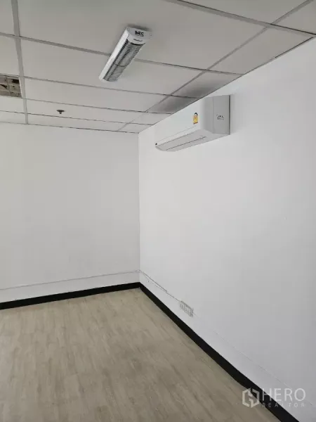 Office Space for rent in Watthana, Bangkok - Split-type air conditioner on a white wall in a small office with LED light and laminate floor.