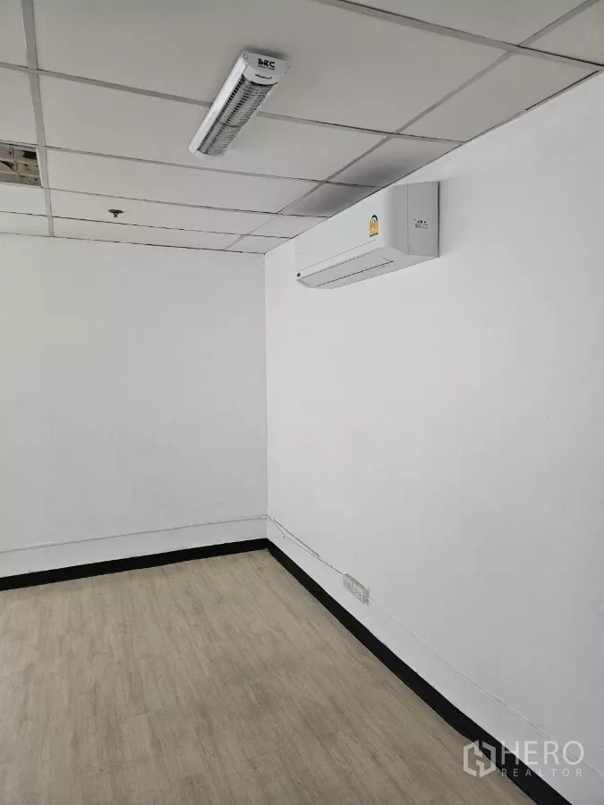 Office Space for rent in Watthana, Bangkok - Split-type air conditioner on a white wall in a small office with LED light and laminate floor.