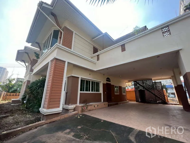 Detached House for rent in Watthana, Bangkok - Covered carport beneath the house with wide driveway and lattice gate.