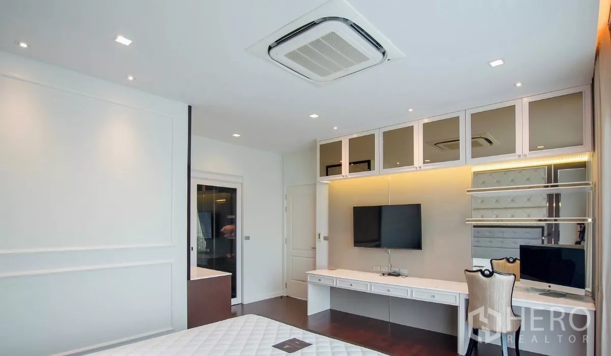 独立式住宅 出租在Bang Bon, Bangkok - 卧室工作区，内置书桌、吊柜与挂墙电视。