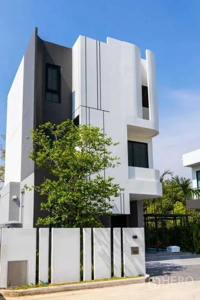 独立式住宅 出租或出售在Lat Krabang, Bangkok - 三层住宅外观另一角度，带围栏与车棚。