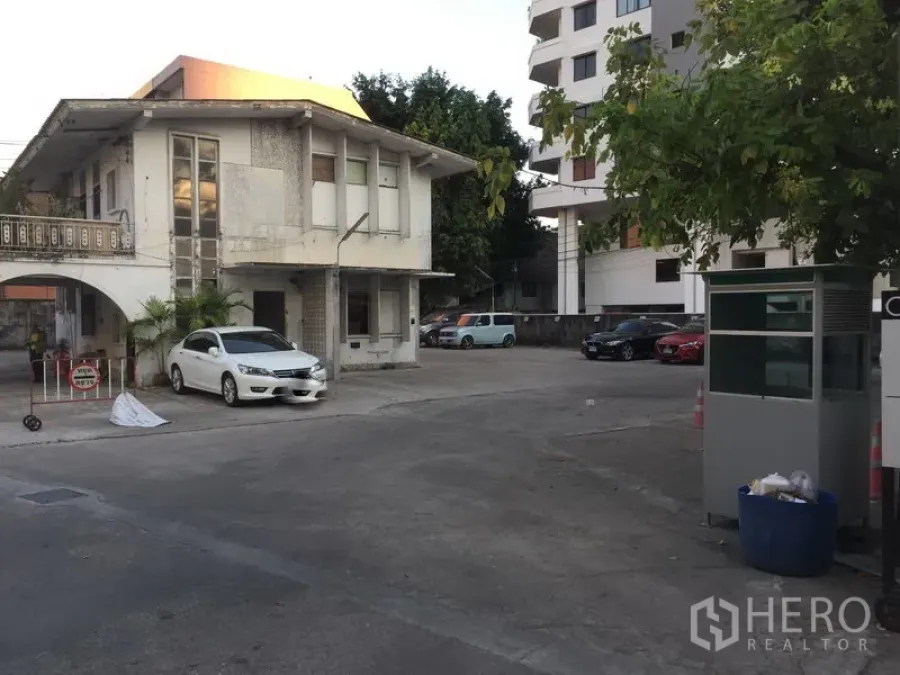 พื้นที่ขายปลีก ให้เช่าในKhlong Toei, Bangkok - อาคารสองชั้นมีซุ้มโค้งและป้อมยาม ข้างลานจอดรถคอนกรีตกว้าง ย่านทองหล่อ