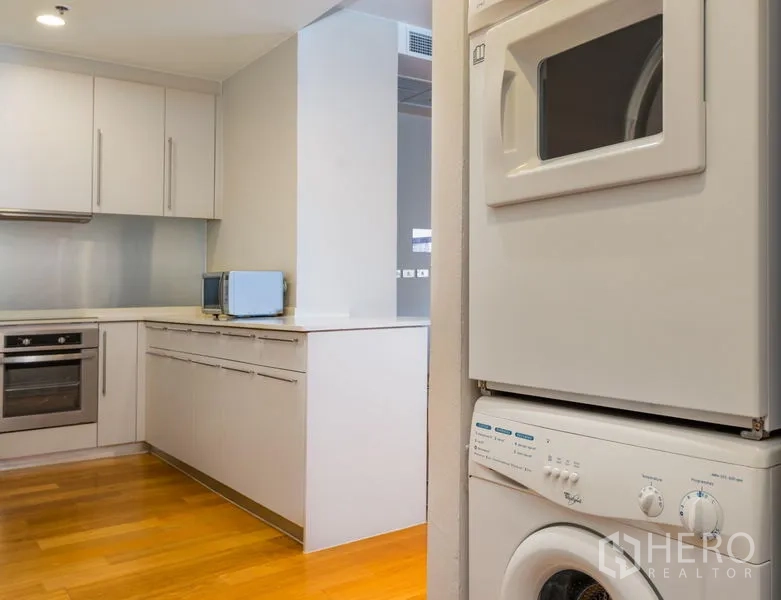 Condominium for rent in Bang Kho Laem, Bangkok - In-unit stacked washer and dryer beside sleek kitchen cabinetry.