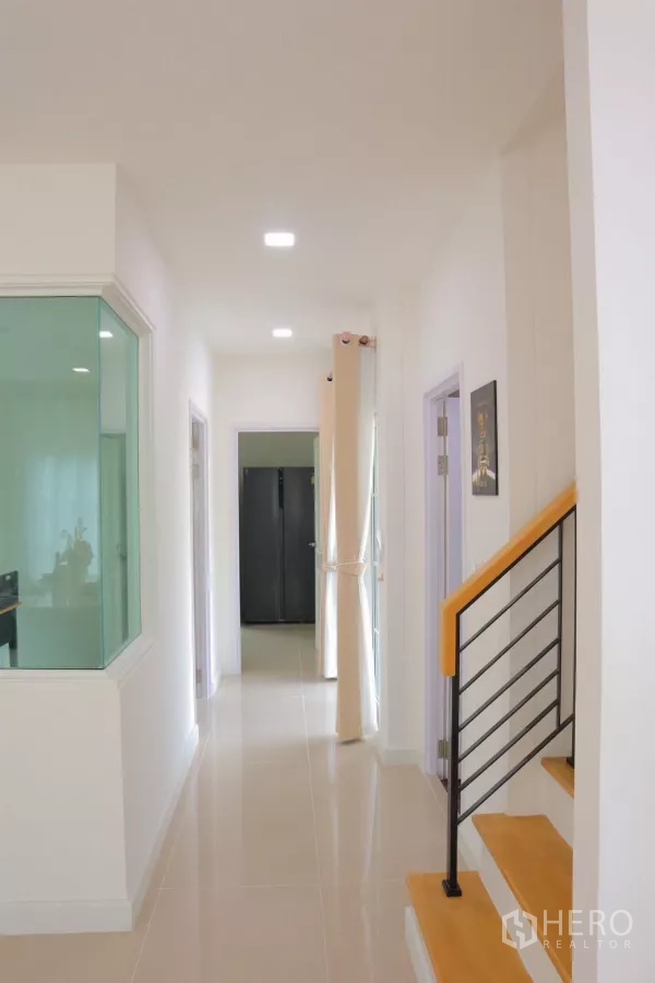 独立式住宅 出租在Bang Phli, Samut Prakan - 一层走廊，带楼梯与玻璃隔断通往各房间。
