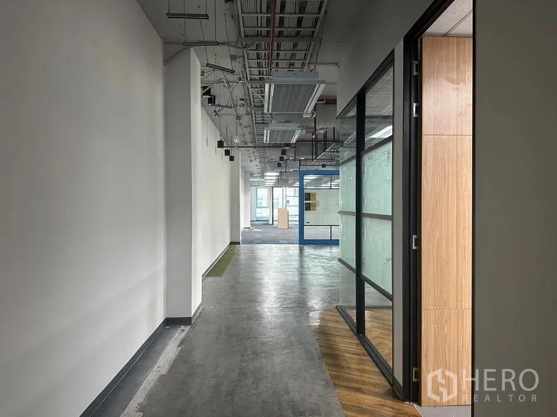 办公空间 出租在Bang Rak, Bangkok - 现代办公走廊，外露管线与玻璃墙的视角。