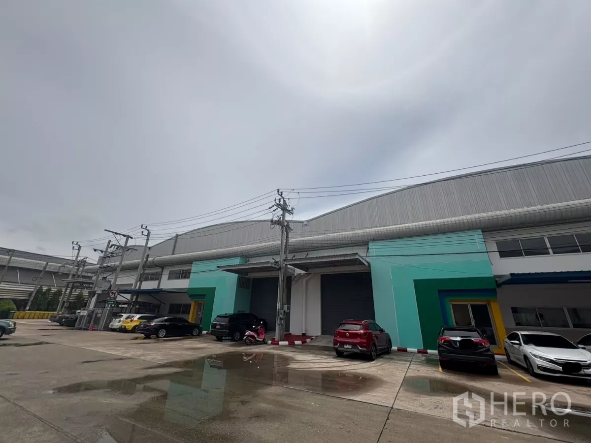Factory for rent in Bang Phli, Samut Prakan - Oblique exterior view of the warehouse building with loading bays, power lines, and car parking.