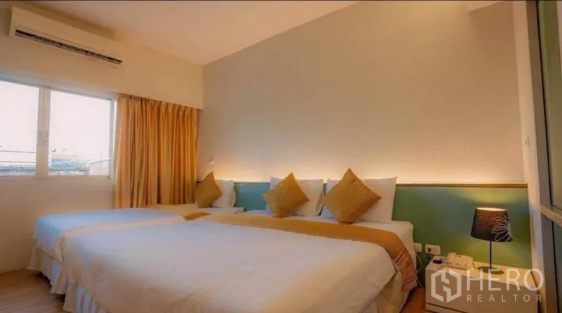 Retail Space for sale in Phra Nakhon, Bangkok - Family room with one king bed and one single bed under warm ambient light.