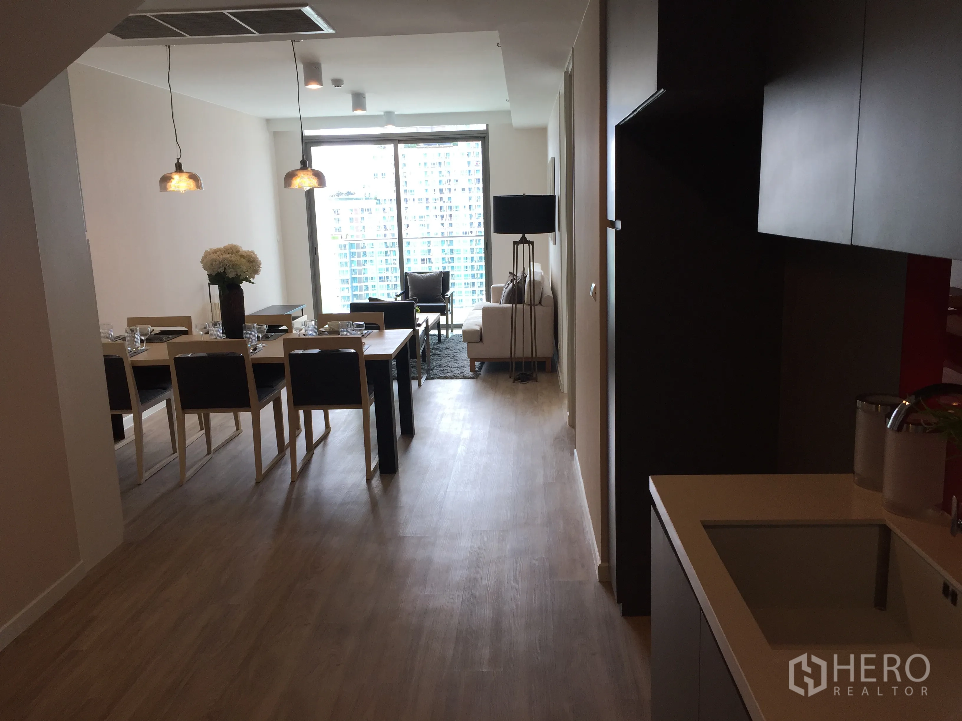 Condominium for sale in Bang Rak, Bangkok - Open-plan kitchen, dining table and living room with floor-to-ceiling windows and city view.