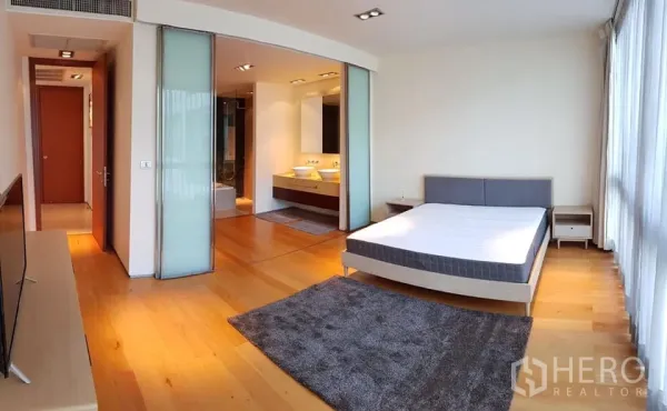 Condominium for rent in Khlong Toei, Bangkok - Large master bedroom with wood floors, big windows and sliding doors opening to the ensuite bathroom.