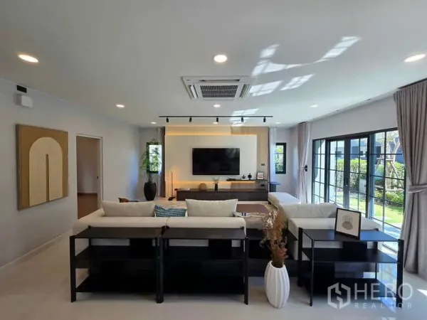 独立式住宅 出租在Bang Phli, Samut Prakan - 客厅配电视背景墙，落地窗景观花园。