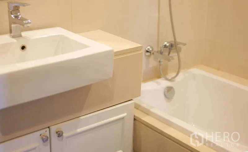 Condominium for rent in Khlong Toei, Bangkok - Bathroom with square basin vanity and built-in bathtub with shower mixer.