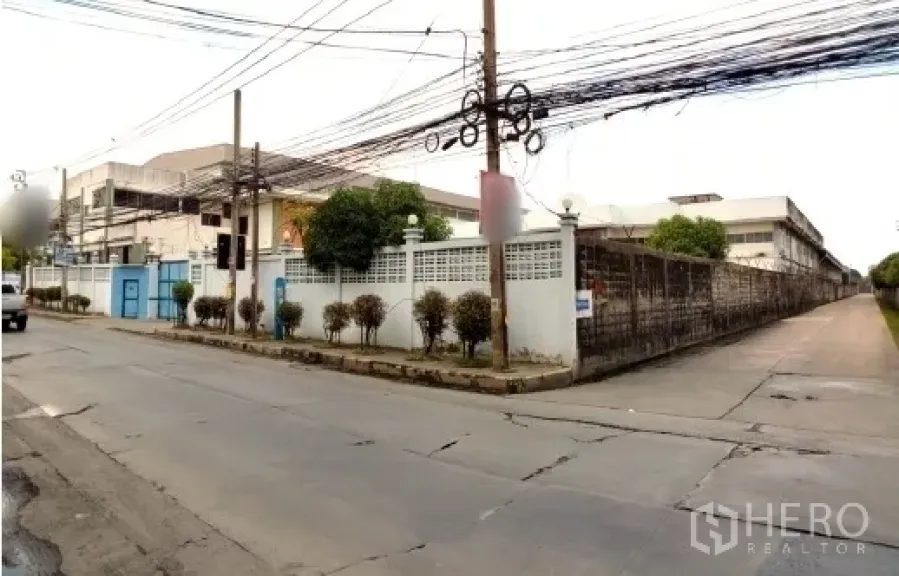 工厂 出售在Bang Phli, Samut Prakan - 临街视角，围墙工厂大门与人行道。
