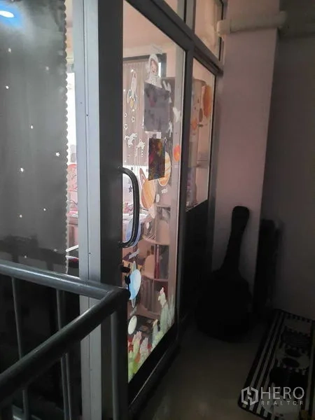 Warehouse for sale in Samut Prakan - Upper-floor glass entry beside the staircase, showing a sliding door with stickers inside the warehouse.