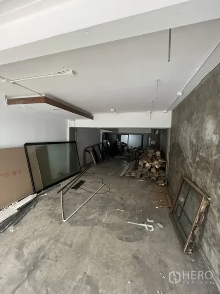 Retail Space for rent in Watthana, Bangkok - Raw retail interior shell with concrete floor, exposed wiring, and stacked materials.