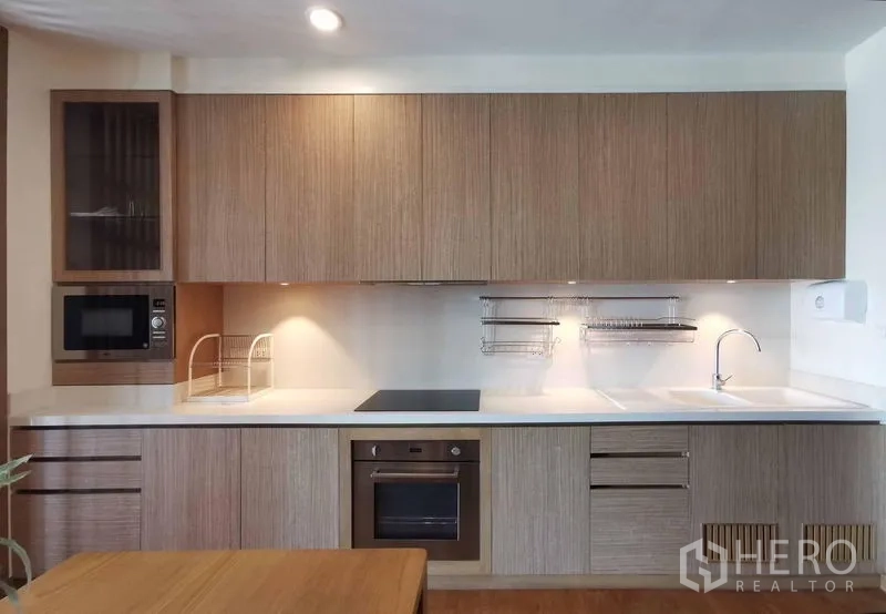 Condominium for rent in Sathon, Bangkok - Full-length linear kitchen with built-in oven, cooktop, microwave and ample cabinetry.