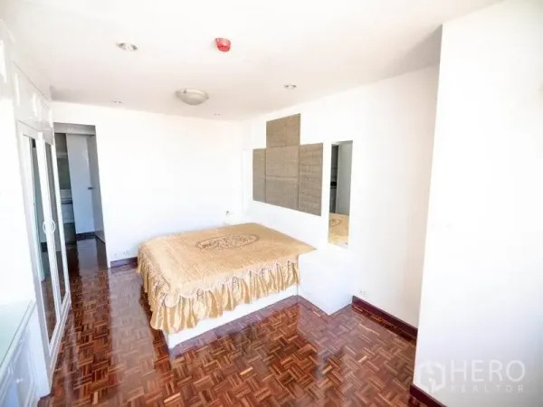 Condominium for rent in Watthana, Bangkok - Large master bedroom with parquet flooring, built-in storage, and ample natural light.