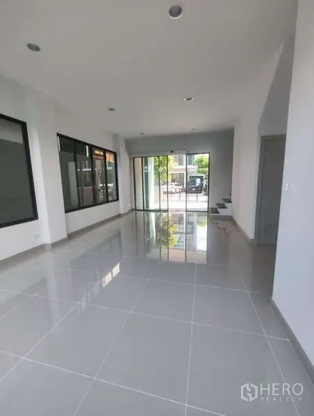 带办公室的家 出租在Bueng Kum, Bangkok - 一层开放式空间，大片窗户与反光地砖，推拉玻璃门通向前方停车区。