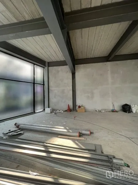 Retail Space for rent in Watthana, Bangkok - Retail corner showing steel columns, large side window and stacked metal pipes on the floor.