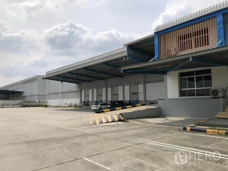 Warehouse for rent in Bang Phli, Samut Prakan - Covered loading area with multiple dock doors, ramp access, and expansive concrete apron.